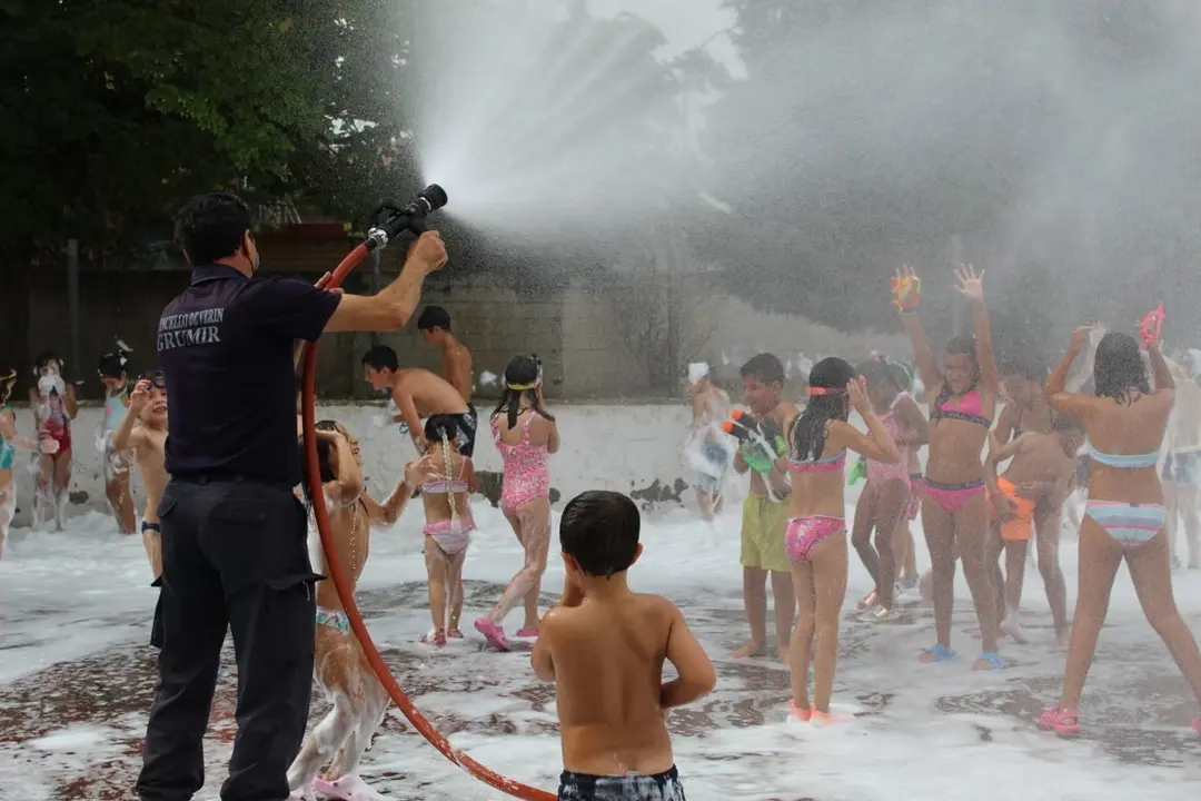Manuel Silva, adecentando con agua a los peque&ntilde;os, despu&eacute;s de haberlos embadurnado con espuma. | FOTO: Xos&eacute; Lois Colmenero.