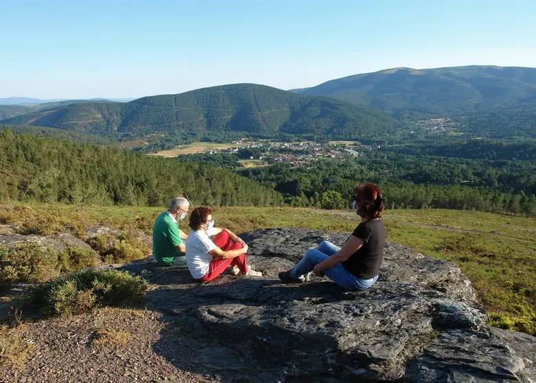 O rexedor lazano, Jes&uacute;s Blanco; a presidenta da Comunidade de Montes de Laza, Rosa L&oacute;pez, e a arque&oacute;loga Nieves Amado, sentadas no enclave recuperado cas vistas da vila &oacute; fondo.