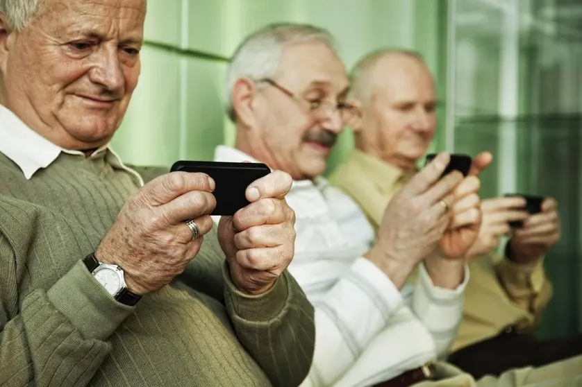 Tres persoas maiores cun Smartphone.