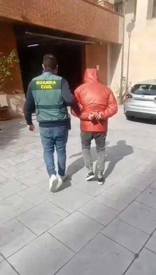 Un agente de la Guardia Civil traslada a uno de los detenidos en la operaci&oacute;n 'GULUX'.