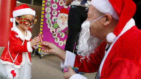 Un profesor extranjero vestido de Papá Noel regala caramelos y chocolates a sus estudiantes durante un evento navideño en un colegio en Bangkok, este miércoles. | FOTO: EFE / Narong Sangnak.