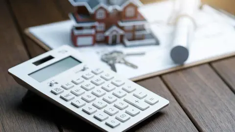 a calculator in front of a Villa house model with a blueprint