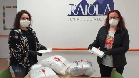 M&oacute;nica D&iacute;az fai entrega de m&aacute;scaras e batas a Nieves Justo, do centro de d&iacute;a Raiola.