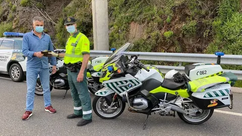 Un conductor luso entrega la cartera con el dinero a un agente de la Guardia Civil de Tr&aacute;fico.