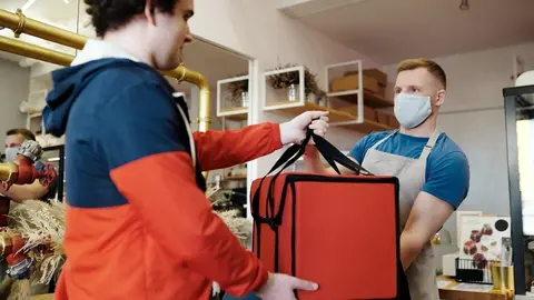  man-in-a-face-mask-handing-over-a-thermal-bag-to-another-man-4393668 