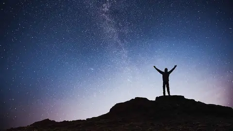 Silhouette young man background of the Milky Way galaxy on a bright star dark sky tone.