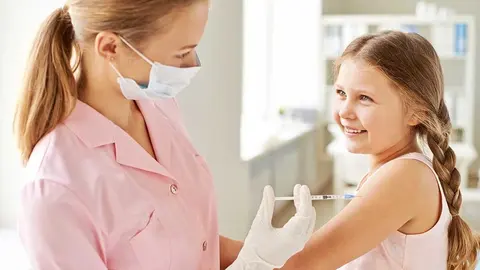 Adorable girl looking at nurse while she making her an injection in clinics
