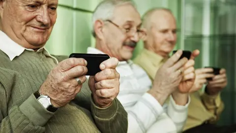Tres persoas maiores cun Smartphone.