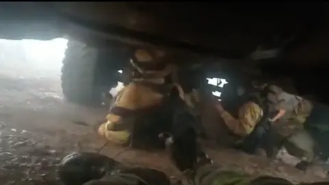 Os bombeiros da Brif de Laza tiveron que refuxiarse da treboada debaixo da s&uacute;a motobomba. | FOTO: Brif de Laza.