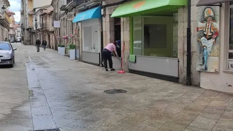 Vecinos y comerciantes de la calle Mayor se preparan para una pr&oacute;xima tromba. | FOTO: Xos&eacute; Lois Colmenero.