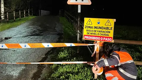 Una voluntaria de Protecci&oacute;n Civil precinta los accesos al puente de A Pousa.