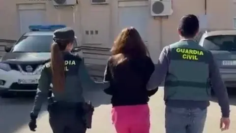 Efectivos de la Guardia Civil trasladan a una de las detenidas por su implicaci&oacute;n en la red criminal.