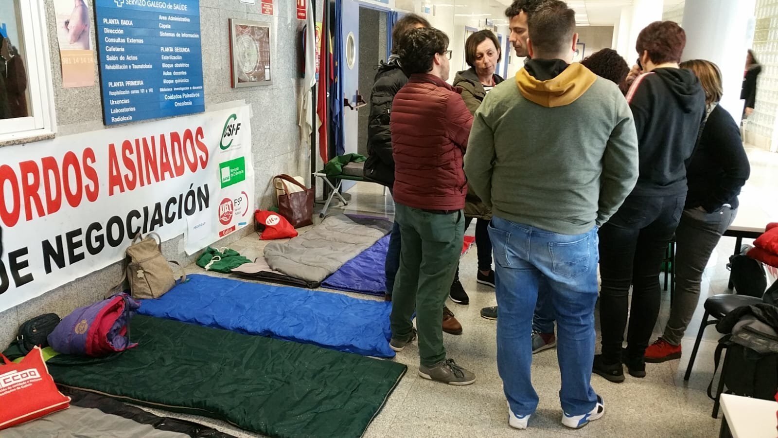 Os candidatos de En Marea conversan cos voceiros sindicais diante das colchoneta que usarán para durmir.