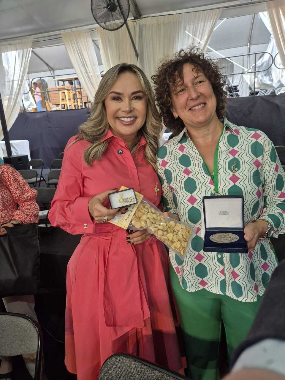 La alcaldesa de O Riós, Eva Barrio, entrega un ejemplar de la castaña local a la regidora de Ibagué, Johana Aranda.